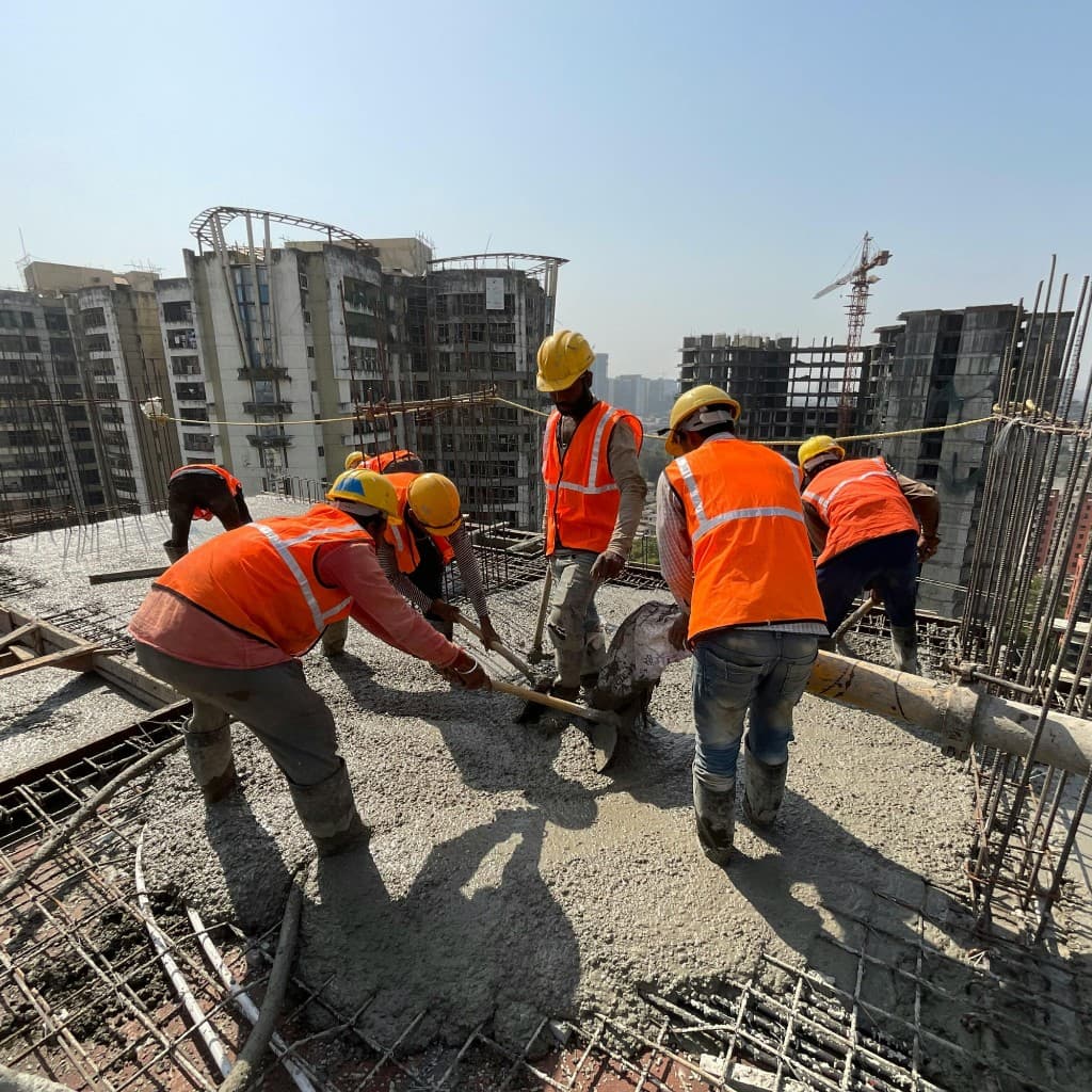Construction crew pouring and leveling concrete on a high-rise site