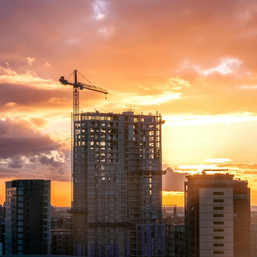 Skyscraper under construction at sunset with tower crane